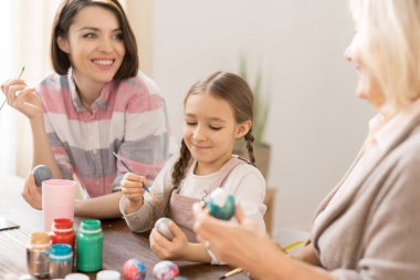Mutlu genç kadın, kızı ve anne tatil önce renkli guaj Paskalya için yumurta boyama