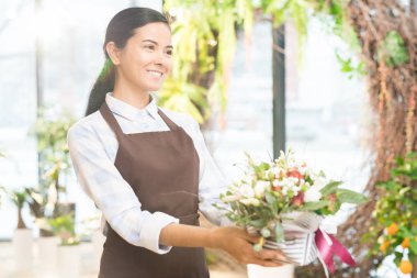 Mutlu genç çiçekçi sunan çeşitli çiçek dükkanında çalışırken grup ile istemci küçük kap