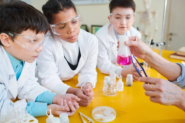 液体1に硬い物質を入れた後 チューブ内の化学反応を見ている好奇心旺盛な小学生のグループ — ストック写真