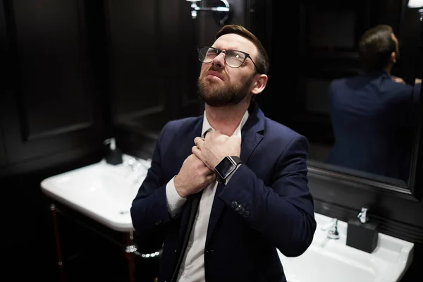 洗面所で彼のネクタイを失う中の喉に彼の手を維持するスーツの現代ビジネスマン — ストック写真