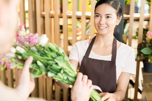 Joven Florista Femenina Sonriente Ropa Trabajo Mirando Cliente Mientras Pasa — Foto de Stock