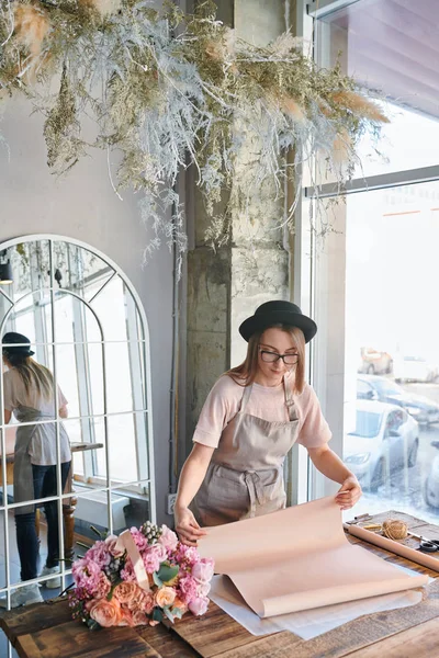 Unga Professionella Kvinnliga Florist Förkläde Och Hatt Står Vid Bordet — Stockfoto