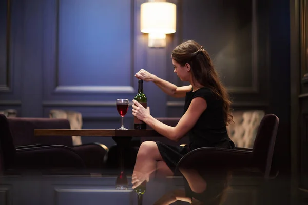若い女性一人で高級レストランのテーブルで座りながら赤ワインのボトルをカバーを開いたり — ストック写真