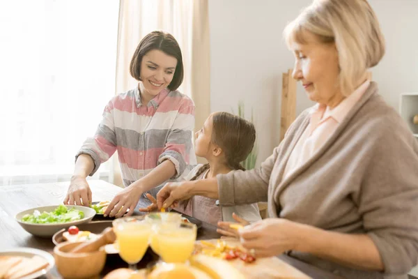 幸せな若い母親と彼女の小さな娘が一緒に朝食を調理しながら キッチンで話をして — ストック写真