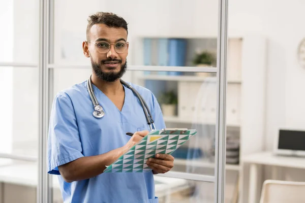 Jovem Barbudo Mestiço Óculos Uniforme Azul Fazendo Anotações Médicas Documento — Fotografia de Stock