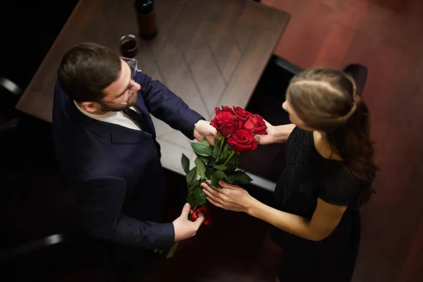 若い男がレストランで彼の恋人に 日付の間に赤いバラの花束を渡すのビュー — ストック写真