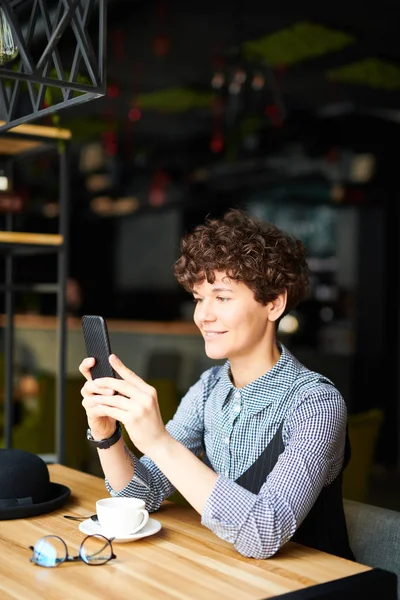 年轻女子穿着休闲装 坐在咖啡馆里 通过智能手机的视频聊天交谈 — 图库照片