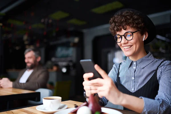 Glückliche Frau Mit Zahmem Lächeln Die Ihrem Smartphone Blättert Während — Stockfoto