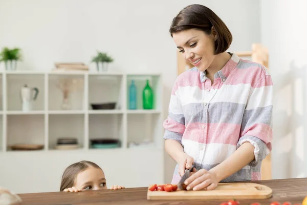 Pequeña Chica Curiosa Asomándose Mesa Cocina Mientras Madre Cortando Tomates — Foto de Stock