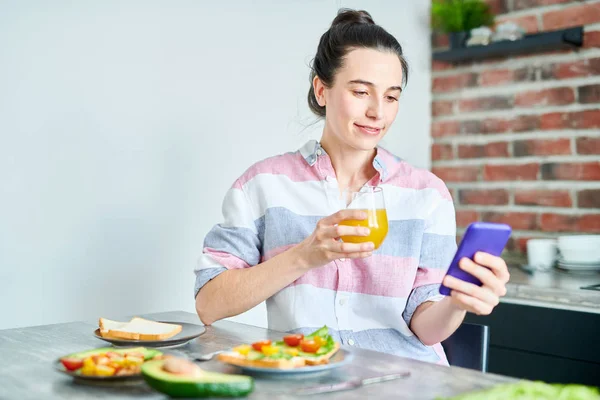 Женщина с помощью смартфона за завтраком — стоковое фото