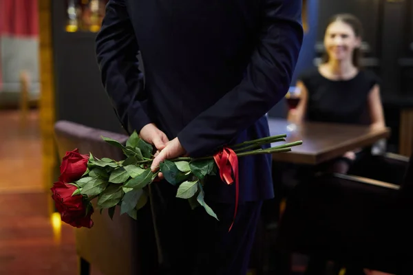 彼のガール フレンドの前に立って後ろに赤いバラの花束を隠してスーツを着たエレガントな男の背面図 — ストック写真