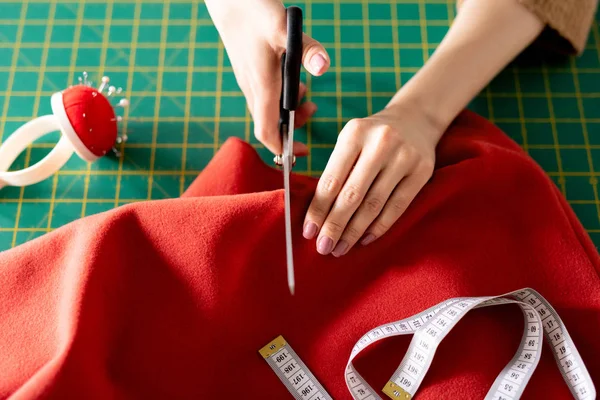 Mãos Jovem Costureira Com Tesoura Cortando Têxteis Vermelhos Enquanto Trabalhava — Fotografia de Stock