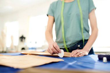 Kadın profesyonel terzi dışarı kesmeden önce tebeşir parçası ile kağıt deseni çevreleyen