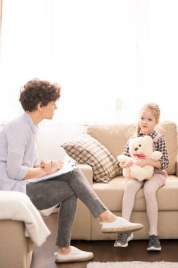 Belge ve küçük öğrenci ev dersi sırasında birbirlerinin önünde koltuklarda oturan genç Casual öğretmen