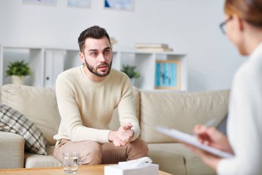 Onun tavsiyelerini dinlerken ve onun sorunları açıklayan Casual sakallı genç adam danışman bakıyor