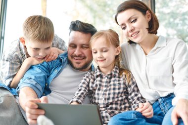 Net meraklı şeyler izlerken touchpad ekran bakarak dört Mutlu genç çağdaş aile