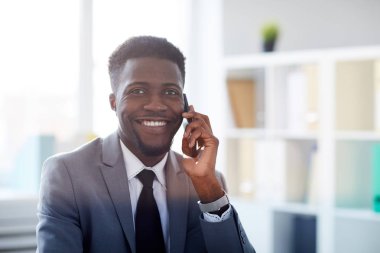 Kamera önünde cep telefonu ararken size bakarak yakışıklı gülümseme ile mutlu genç Ajan