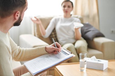 Onun önünde hastanın hikayesini dinlerken belgeli profesyonel danışman yapma notları