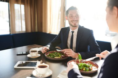 Formalwear Mutlu genç komisyoncu meslektaşı ile kafede öğle yemeği ve bazı çalışma anları tartışıyor