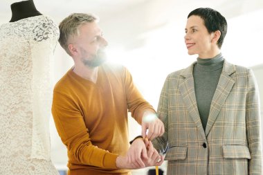 Ceket terzi mutlu müşteri terzilik dükkanda bilek kapalı önlemleri alma sürecinde ona bakıyor