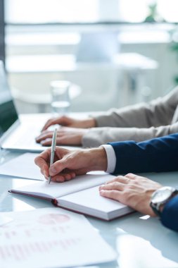 Genç ofis yöneticilerinden biri, meslektaşının arka planında not defterine organizasyon notları yazarak