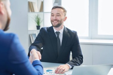 Mutlu genç başarılı işadamı ofiste toplantıda yeni ortaklar veya meslektaşının el sıkışma