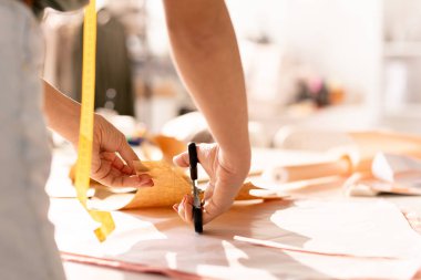 Dikiş atölyinde işyeri üzerinde bükme sırasında makas kağıt deseni kesme ile genç terzi elleri