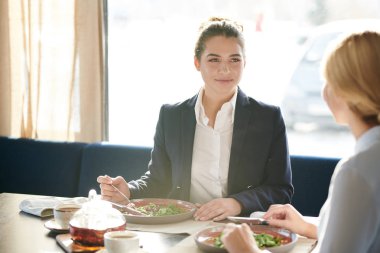Genç kendine güvenen iş kadını ve meslektaşı kafede öğle yemeği sırasında bazı çalışma organizasyon anları tartışıyor