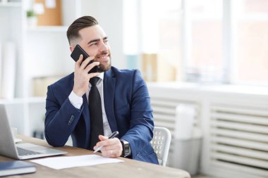 Genç başarılı CEO 'su veya iş lideri harika insanlar ofiste masada oturan ve telefon müşterilerinden biriyle konuşmak