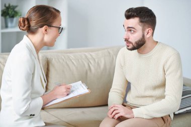 Bireysel oturumda onun sorunlarının tartışma sırasında danışman bakıyor genç rahat adam