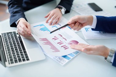 Ekonomistlerden biri, çalışma toplantısında iş arkadaşına açıklarken kağıt üzerinde çizelgeye işaret ediyor