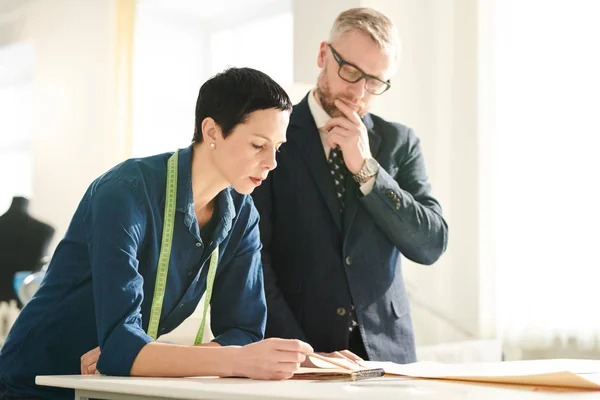 Schneiderin Beugt Sich Über Schreibtisch Während Sie Skizzen Notizblock Macht — Stockfoto