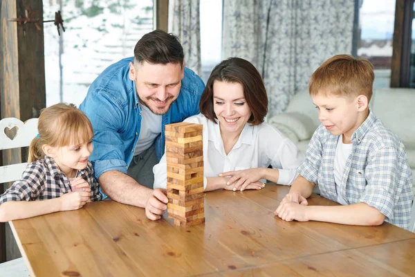 年轻人要带走一块塔的木砖 同时和家人在桌子上玩休闲游戏 — 图库照片