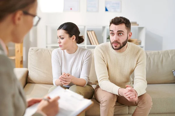 Genç kocası ve karısı koltuk üzerinde psikolog önünde oturan ve durum hakkında onu tavsiye dinleme