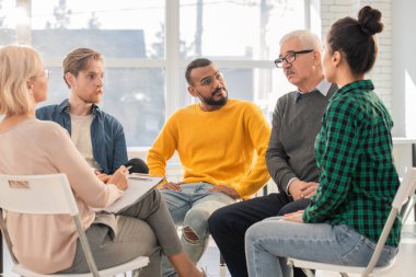 Psikolojik oturum sırasında daire içinde oturan ve etkileşim çeşitli yaşlardan çok ırklı insanların grubu