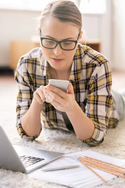 Innehåll Fundersam Ung Kvinna Glasögon Liggande Mattan Och Använda Smartphone — Stockfoto