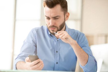 Ciddi veya gergin genç ofis yöneticisi o anlayamıyorum akıllı telefon mesajı veya promosyon okuma