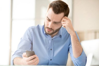İşyeri tarafından mesaj veya bildirim okurken akıllı telefon ekranına bakan pensive veya yorgun işadamı