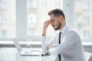 Young tired and tense manager trying to concentrate while working over project and thinking of ideas