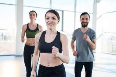 Spor giyim genç neşeli dostu aktif insanlar grubu önünde güzel kız ile spor salonunda egzersiz zevk