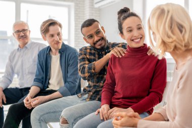 Oturumda onunla konuşurken sarışın olgun kadın bakarak casualwear Mutlu genç kültürlerarası çift