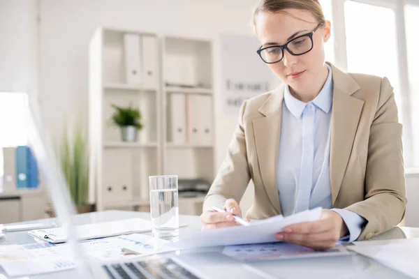 現代のオフィスの机に座り 会議の準備をしながら書類を分析するメガネで深刻な集中ビジネス女性 — ストック写真