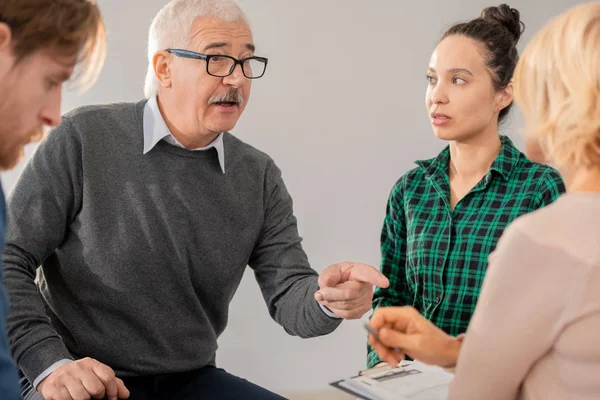 Hombre Mayor Gafas Apuntando Psicoterapeuta Entre Compañeros Grupo Mientras Explica — Foto de Stock