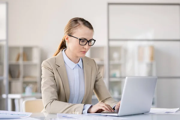 Jovem Ocupada Séria Óculos Sentada Mesa Escritório Moderno Digitando Teclado — Fotografia de Stock