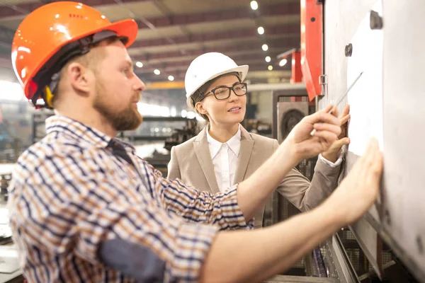 Dos Jóvenes Ingenieros Confiados Cascos Mirando Bocetos Mientras Uno Ellos — Foto de Stock