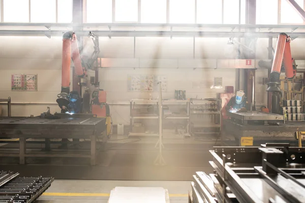 バックライト付き工場内で溶接作業を行うユニフォームと保護ワークウェアの2つの現代的な溶接機 — ストック写真
