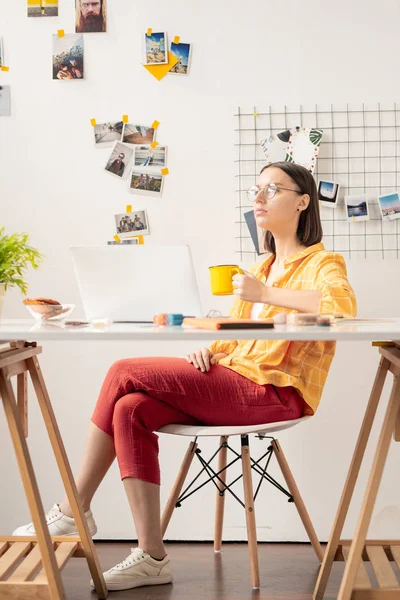 年轻的当代女商人 穿着便服 坐在办公桌前喝茶或喝咖啡 在笔记本电脑前受到启发 — 图库照片