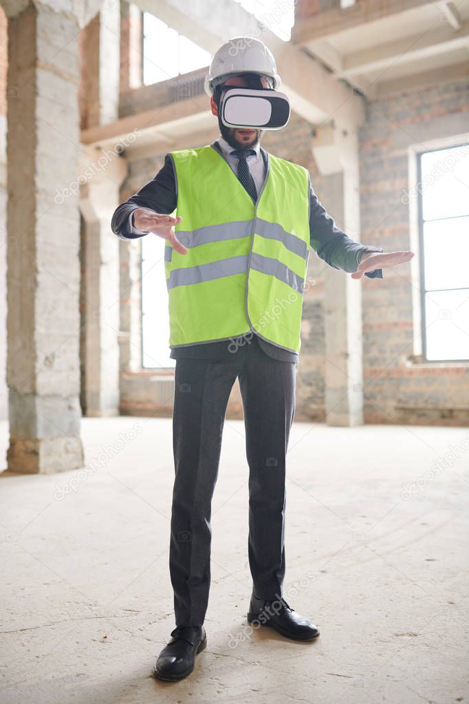 Young contemporary foreman or engineer in vr headset and workwear working in virtual reality inside unfinished building