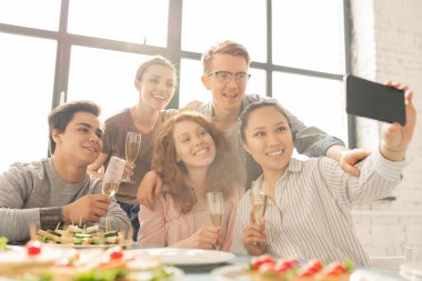 Ev partisinin tadını çıkarırken masa servisi ile selfie yapan içeceklerle genç neşeli arkadaşlar grubu