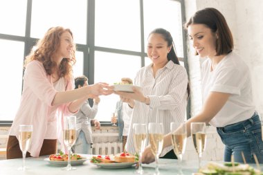 Parti öncesi misafirler için masa hizmet ederken arkadaşlarından birine sandviç ile plaka geçen Pretty kıvırcık kız